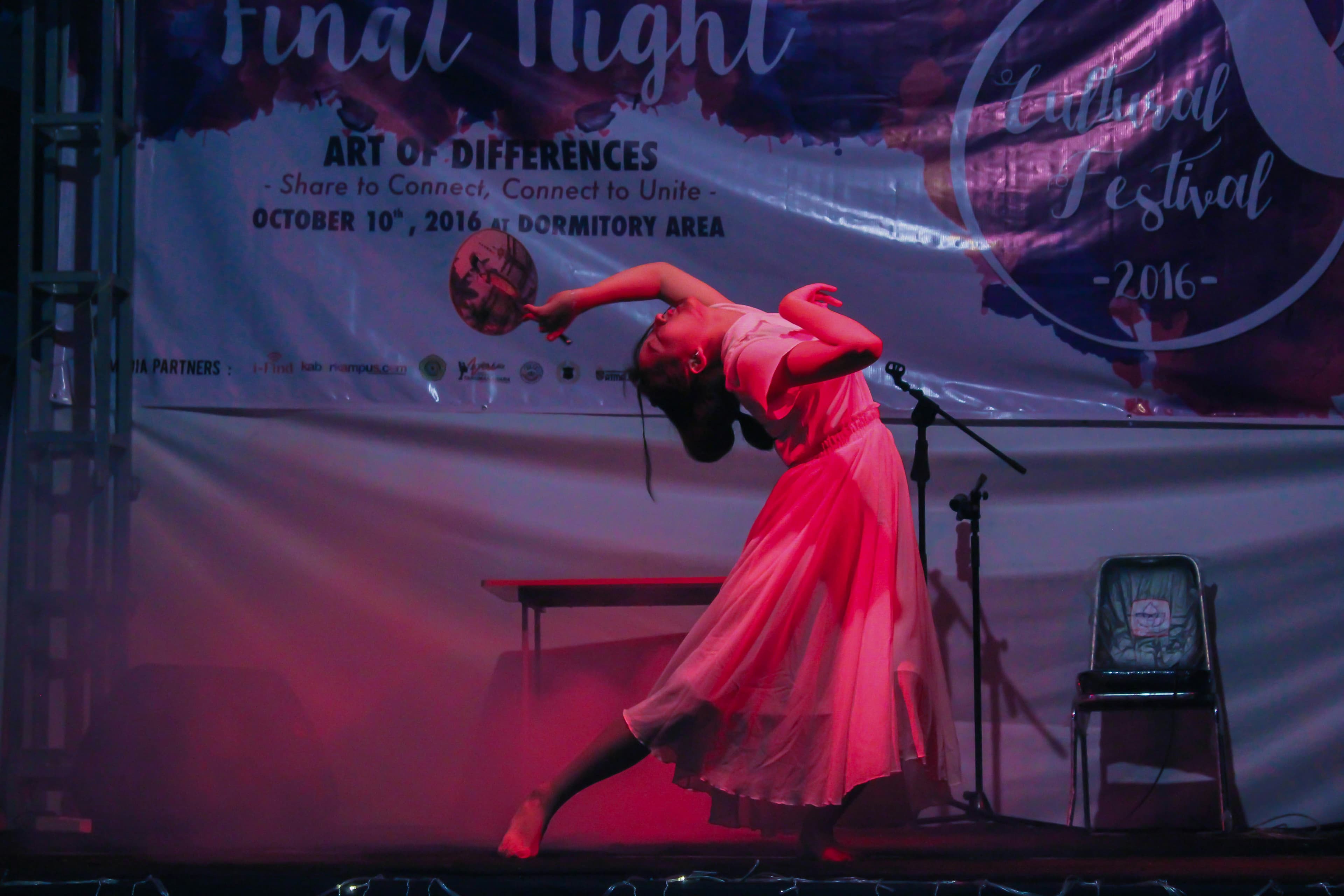 Woman in pink dress performing in stage with a traditional fan